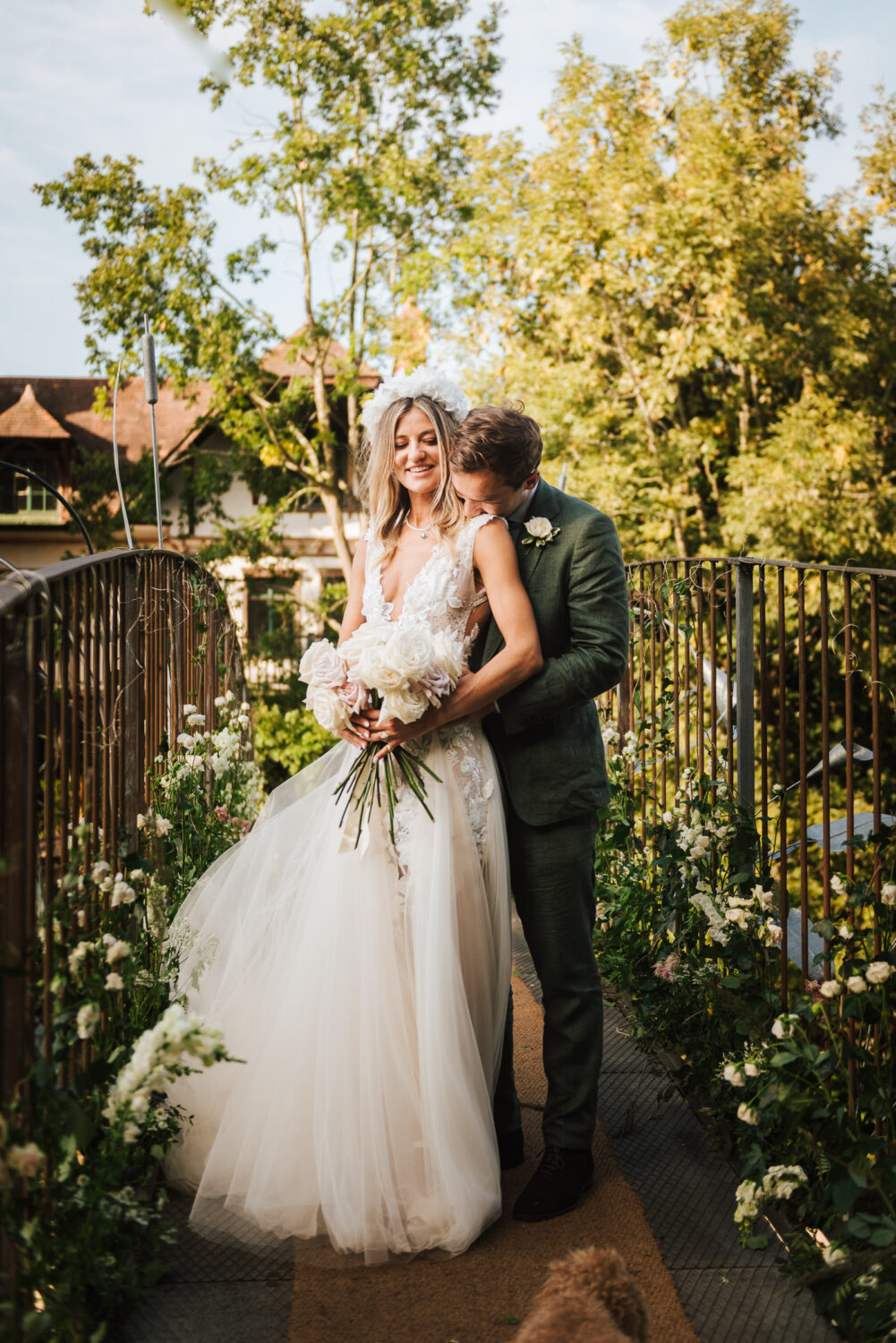 A bride and groom kissing on a bridge in summer