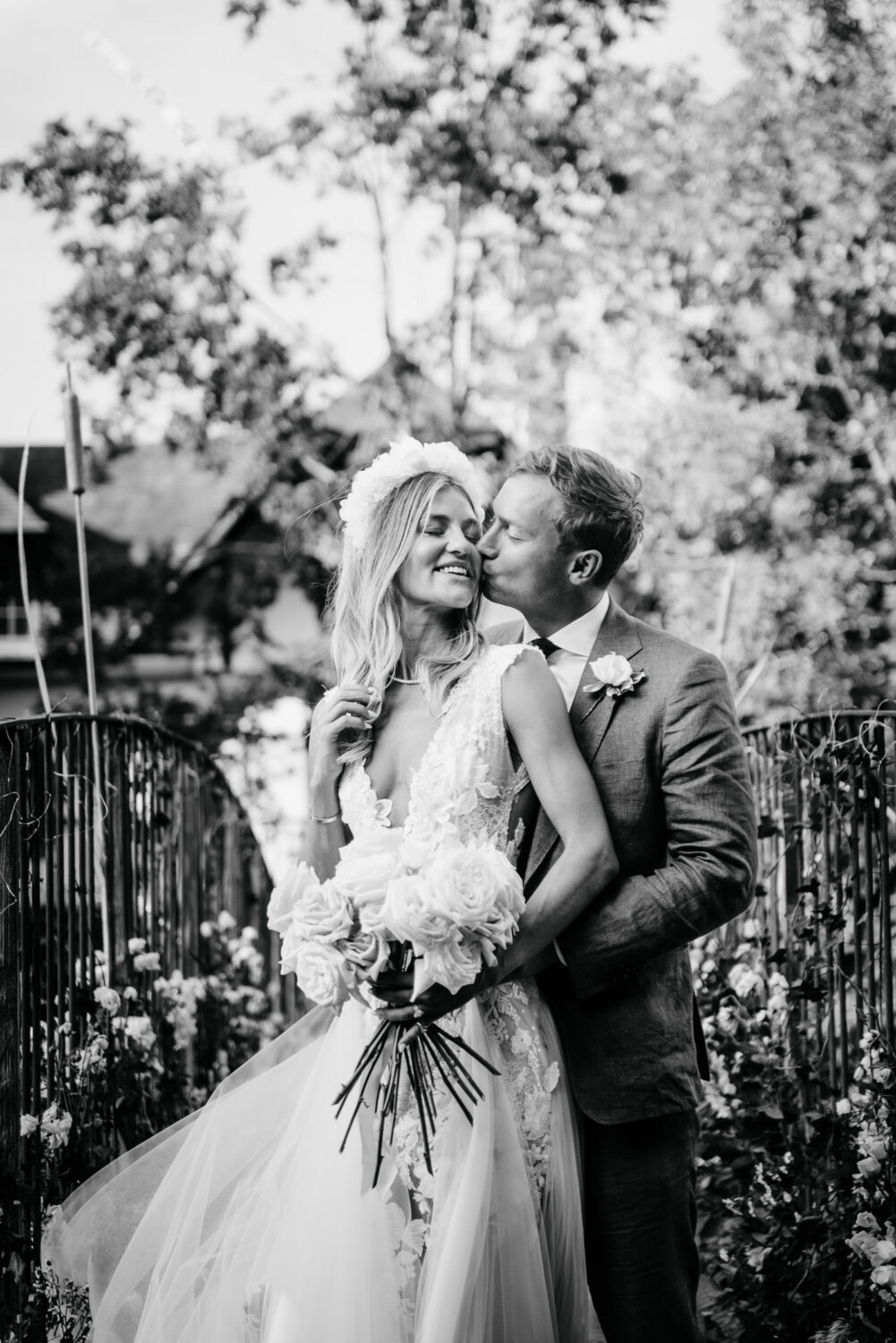 A black and white image of a couple kissing on their wedding day