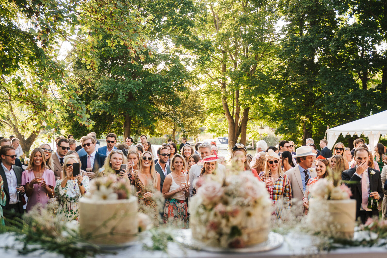 All the guests at a wedding waiting for the cakes to be cut by the happy couple