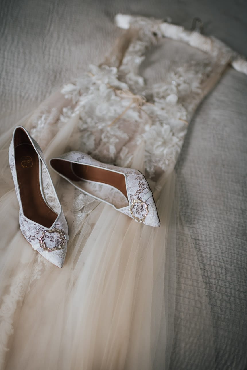 A beautiful lace wedding dress and wedding shoes on a bed
