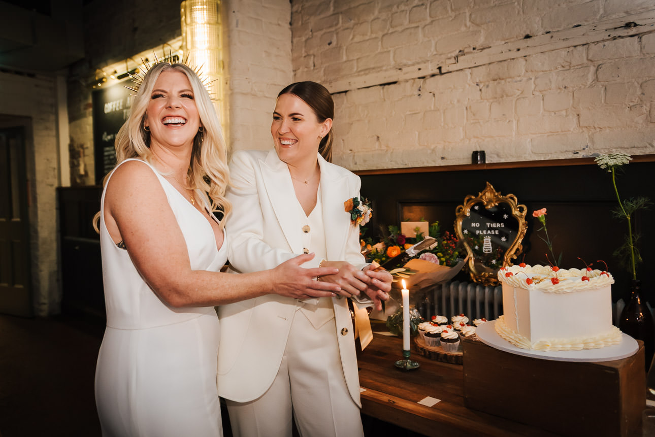 A same sex couple cutting their wedding cake