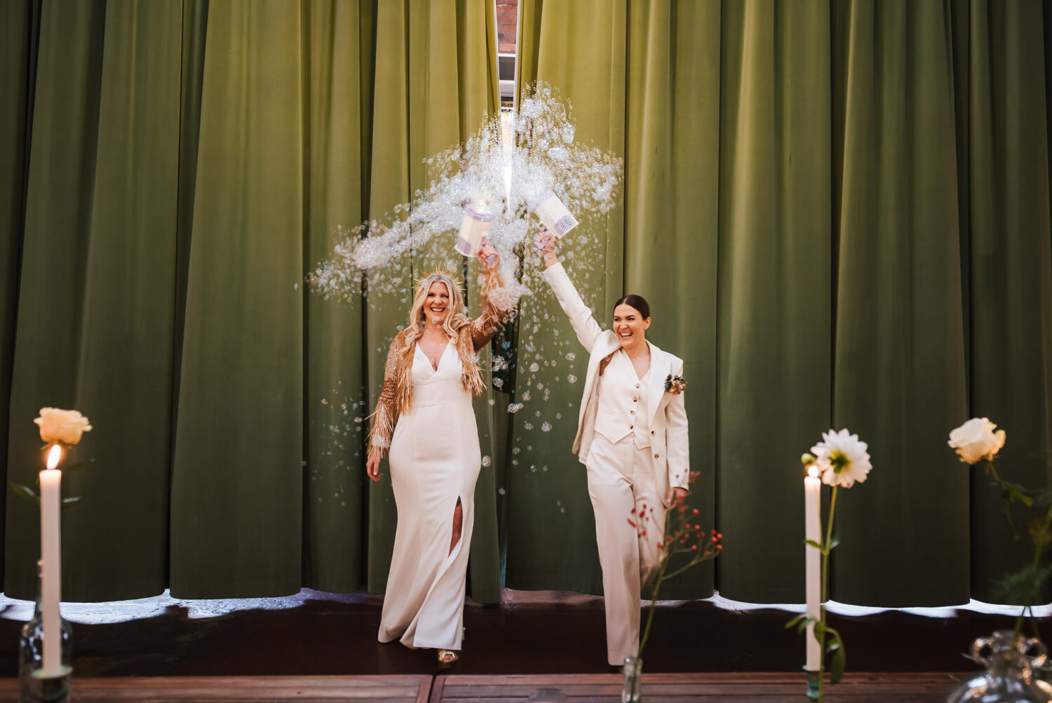 A bride and her bride walking into their wedding with bubble guns