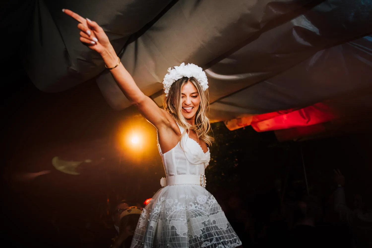 A bride in white being lifted on the crowds shoulders and dancing