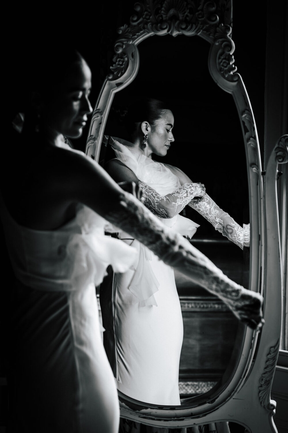 Black-and-white portrait of a bride adjusting her lace gloves in a mirror at a Yorkshire wedding
